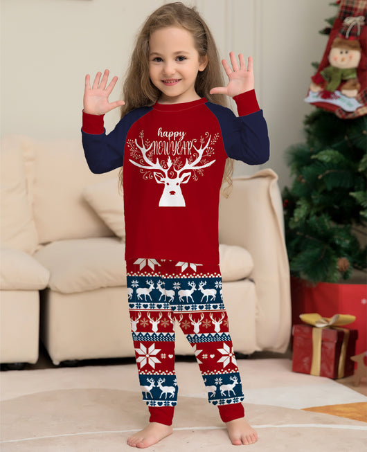 Child wearing a red and navy blue Christmas pajama set with a white reindeer and "happy NEW YEAR" text on the top, and fair isle pattern pants. - Image 11