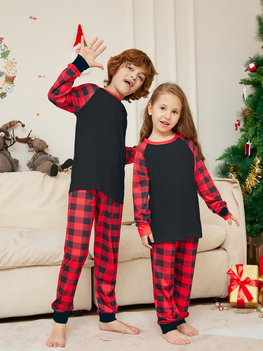 Family of four wearing matching black and red buffalo plaid pajamas in a festive Christmas living room. - Image 10