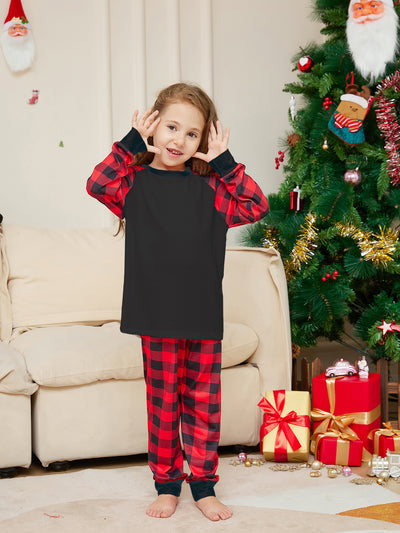Family of four wearing matching black and red buffalo plaid pajamas in a festive Christmas living room. - Image 12