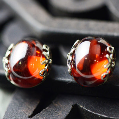 Silver ring with a large, round, deep red gemstone set in an ornate filigree bezel, displayed on a textured surface. - Image 4