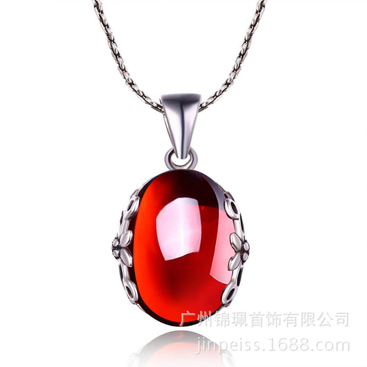 Silver ring with a large, round, deep red gemstone set in an ornate filigree bezel, displayed on a textured surface. - Image 6