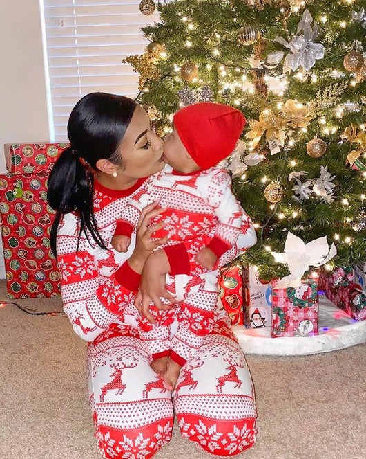 Family of eight wearing matching red and white Christmas pajamas with reindeer and snowflake patterns in a living room. - Image 11
