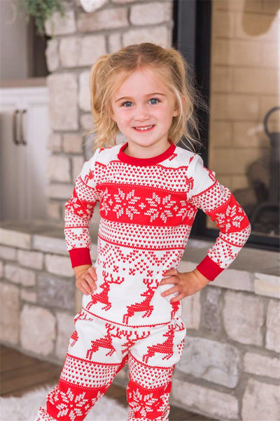 Family of eight wearing matching red and white Christmas pajamas with reindeer and snowflake patterns in a living room. - Image 12