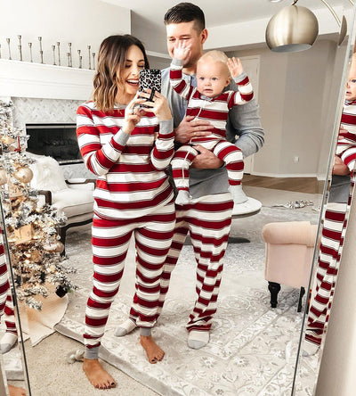 Family of three in matching red and white striped Christmas pajamas, posing for a mirror selfie in a festive living room. - Image 10