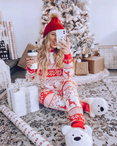 Family of eight wearing matching red and white Christmas pajamas with reindeer and snowflake patterns in a living room. - Image 21