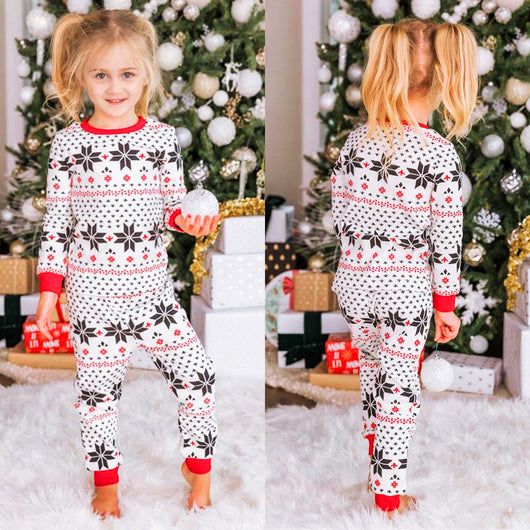 Family of six wearing matching black, white, and red fair isle print Christmas pajamas with red cuffs and collars. - Image 24