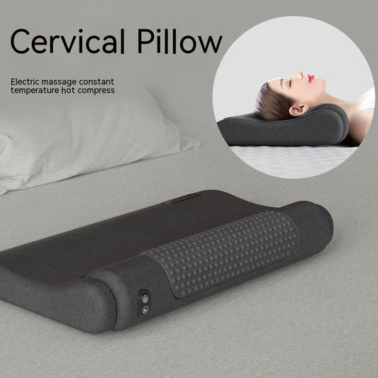 Dark gray cervical spine pillow with light gray textured massage area and power button on a light gray surface.