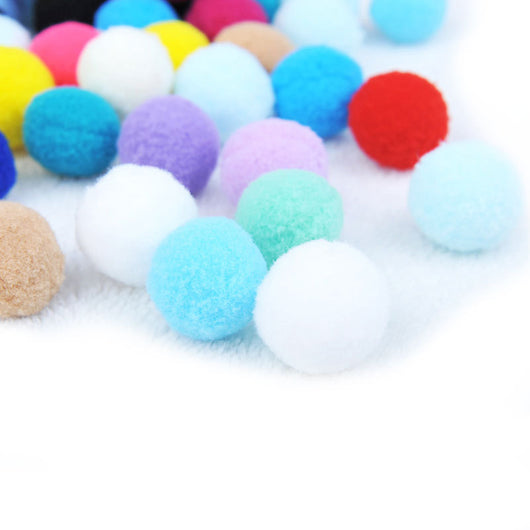 Assortment of colorful plush pom-pom balls, some in a wooden box, others scattered on a white surface. - Image 2