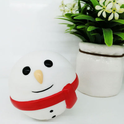 White snowman pet toy with black eyes, orange nose, smiling mouth, and red scarf, next to a potted plant. - Image 8