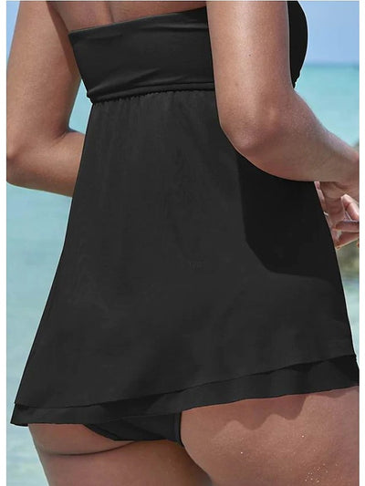 Woman in a brown strapless ruched one-piece swimdress with a flowing skirt, standing in shallow ocean water. - Image 11