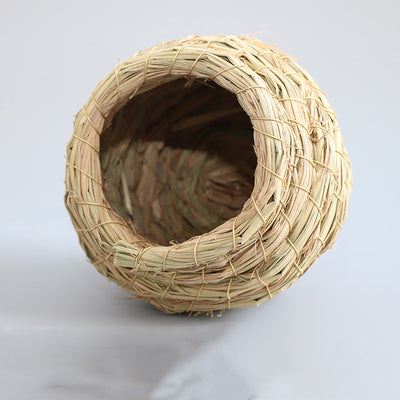 Hand-woven straw bird nest with a round entrance, designed for small birds and pets, shown with a colorful bird flying towards it. - Image 4