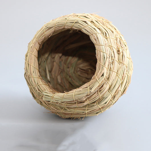 Hand-woven straw bird nest with a round entrance, designed for small birds and pets, shown with a colorful bird flying towards it. - Image 4