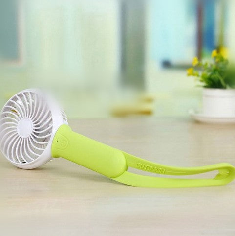 Lime green and white mini USB portable fan with a flexible strap, lying on a light wooden surface. - Image 4