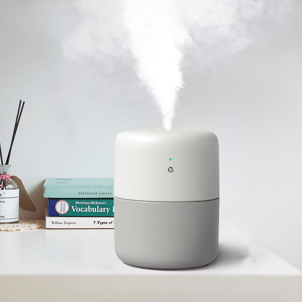 Coral desktop humidifier with a modern cylindrical design, featuring a green indicator light and a power button.