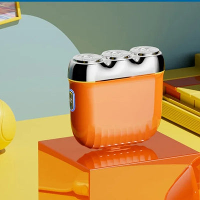 Orange mini electric shaver with three silver floating cutter heads, a blue power button, on a translucent orange block. - Image 9