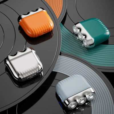 Orange mini electric shaver with three silver floating cutter heads, a blue power button, on a translucent orange block. - Image 21