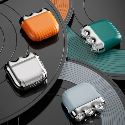 Orange mini electric shaver with three silver floating cutter heads, a blue power button, on a translucent orange block. - Image 24