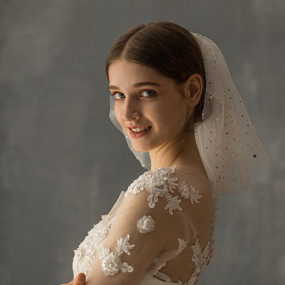 White multi-layer short bridal veil with gold star embellishments, worn by a model in a white lace wedding dress.
