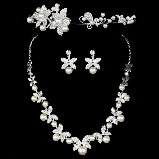 Elegant bridal jewelry set featuring a pearl and rhinestone floral necklace with matching drop earrings on a model.