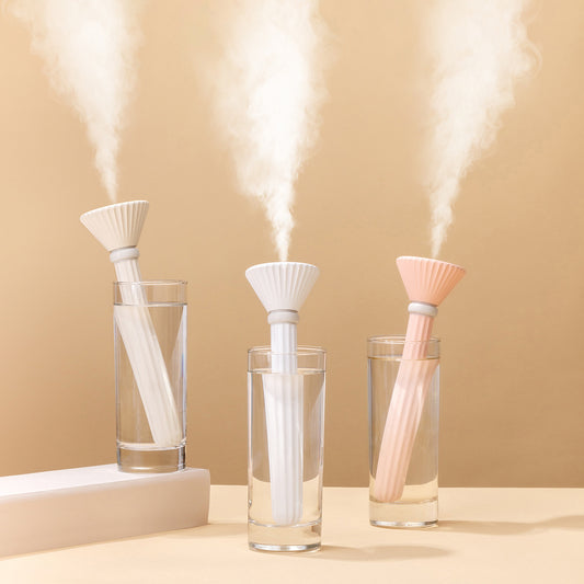 Beige and white USB ultrasonic humidifier with a fluted conical top and a cylindrical body with a water level window.