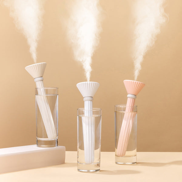 Beige and white USB ultrasonic humidifier with a fluted conical top and a cylindrical body with a water level window.