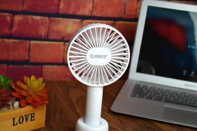 White ORICO FH1 handheld USB fan with charging dock, USB cable, and user manuals on a wooden desk. - Image 5