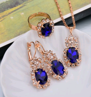 Rose gold-toned necklace, earrings, and ring set with large oval clear gemstones surrounded by smaller stones. - Image 5