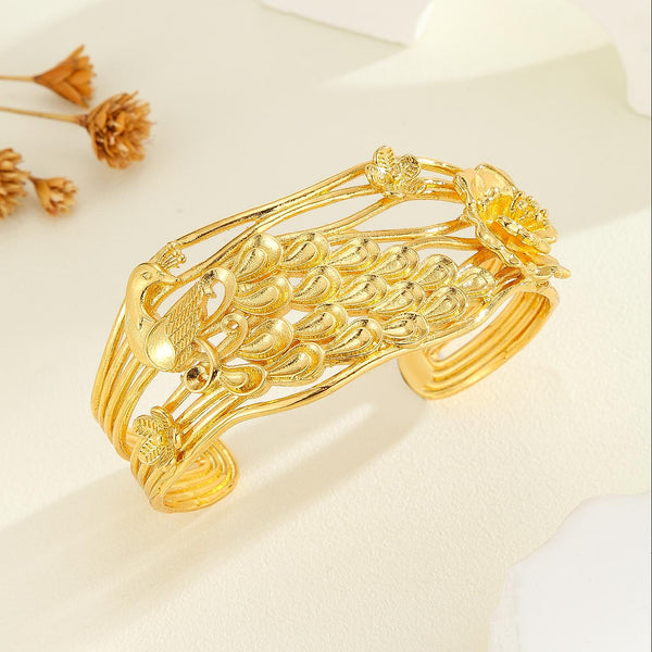 Vintage luxury gold-colored cuff bracelet with intricate carved peacock and flower patterns, featuring multiple bands.