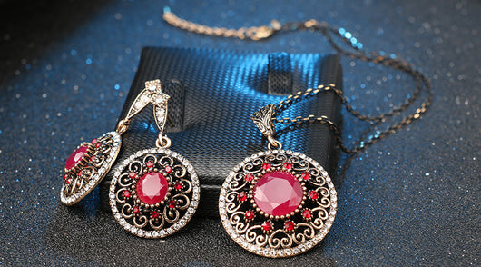 Vintage-style jewelry set with a necklace and matching drop earrings. Features red and clear gemstones in an antique gold-tone filigree design. - Image 10