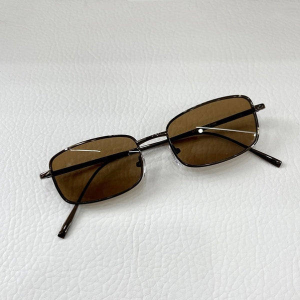 Retro gold metal frame sunglasses with light brown rectangular lenses, displayed on a white surface.