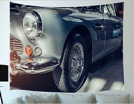 Car tapestry featuring a close-up of a metallic grey-blue vintage car's front, headlight, and wire wheel.
