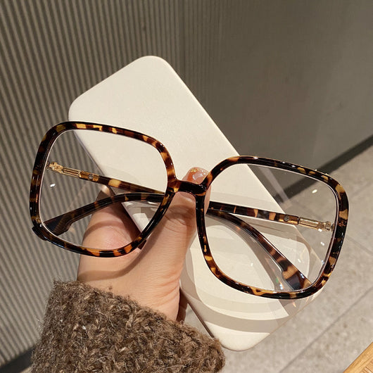 Black oversized square anti-blue light glasses with clear resin lenses and gold metal frame details, held by a hand. - Image 5