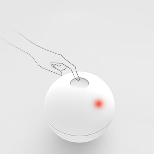 White smart automatic interactive cat toy ball with a red indicator light, being activated by a hand pressing its button. - Image 5