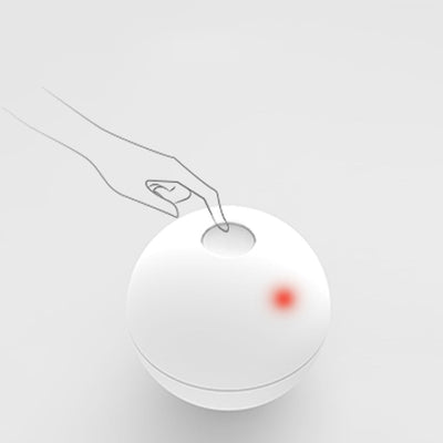 White smart automatic interactive cat toy ball with a red indicator light, being activated by a hand pressing its button. - Image 5