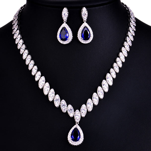 Silver-toned necklace and earring set with red teardrop stones and clear marquise-cut accents on a black display. - Image 5