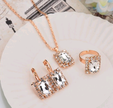 Rose gold-toned necklace, earrings, and ring set with large oval clear gemstones surrounded by smaller stones. - Image 29