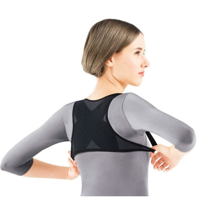 Woman wearing a black posture correction belt with criss-cross back design over a grey shirt, adjusting the strap. - Image 8