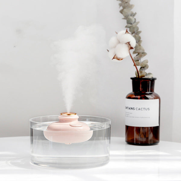 Three 'Drift bottle' humidifiers in white, mint green, and pink, floating in water and emitting mist.