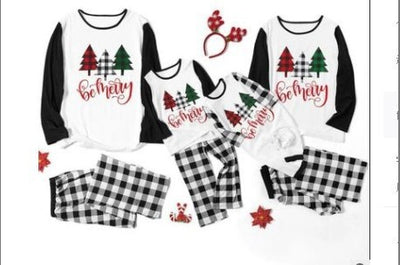 Matching family Christmas pajamas with white tops, black sleeves, buffalo plaid trees, and 'be merry' text. - Image 5