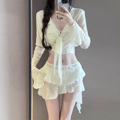 White four-piece bikini swimsuit set for women, featuring a long-sleeve tie-front top and tiered ruffle skirt.