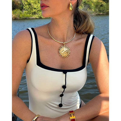 Woman in a white one-piece swimsuit with black trim and decorative buttons, sitting on a boat. - Image 8
