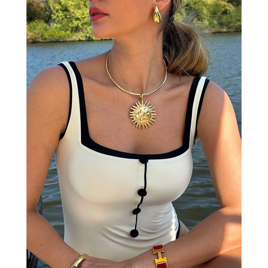 Woman in a white one-piece swimsuit with black trim and decorative buttons, sitting on a boat. - Image 8