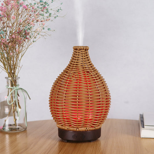 Mini ultrasonic aroma diffuser with a brown hollow rattan-style body and a white base, featuring control buttons.