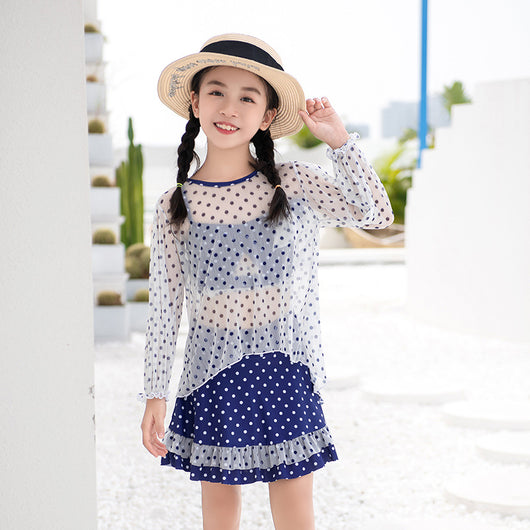 Woman in a cute and sweet three-piece swimsuit with a sheer white polka dot long-sleeve top and navy blue polka dot swim skirt. - Image 13