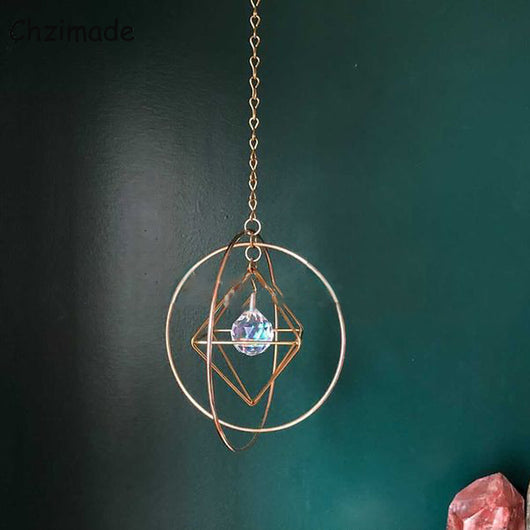 Geometric iridescent suncatcher with a gold frame and dangling crystal pendants, held in a hand, creating rainbow light. - Image 10