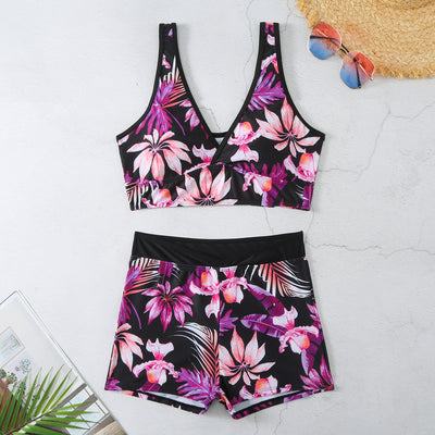 Two-piece swimsuit with a black background and vibrant pink and purple tropical floral print. Features a V-neck crop top and high-waisted boxer shorts. - Image 9