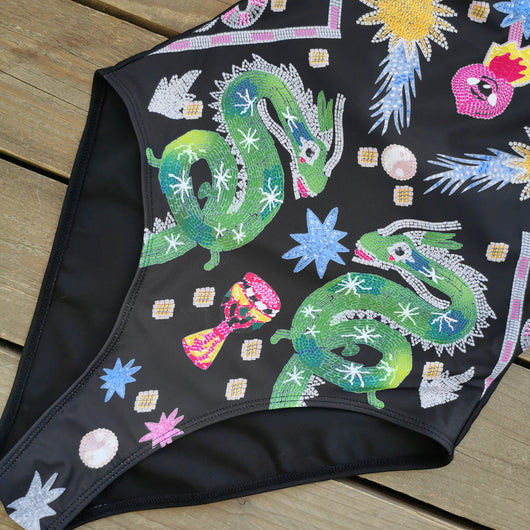 Black one-piece swimsuit for women featuring a vibrant multi-color print with dragons, suns, moons, and stars. - Image 9