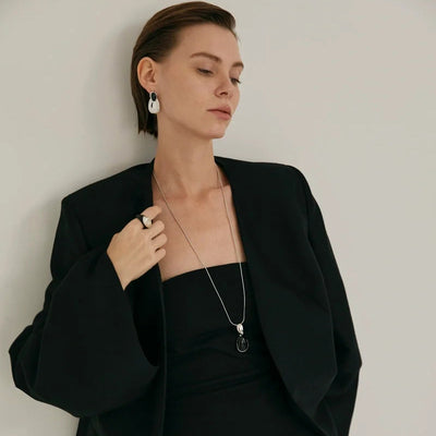 Pair of gold-toned irregular earrings with black onyx-like inserts, featuring a modern, abstract design. - Image 3