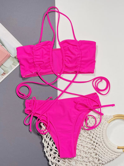 Neon pink lace-up bikini with a bandeau top and high-cut bottom, laid flat on a split gray and white background. - Image 14