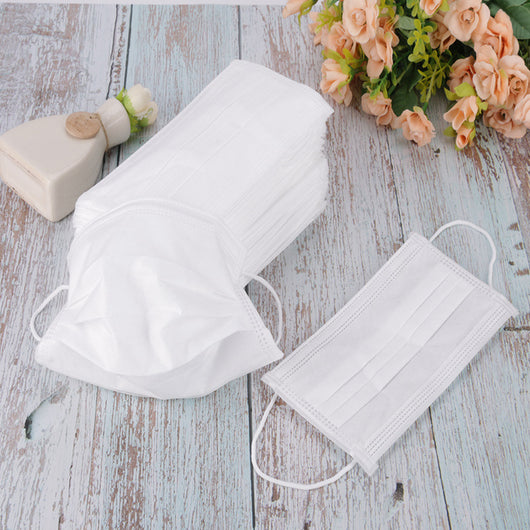 Stack of pink disposable non-woven face masks, with one unfolded and one folded, on a light wood surface. - Image 3